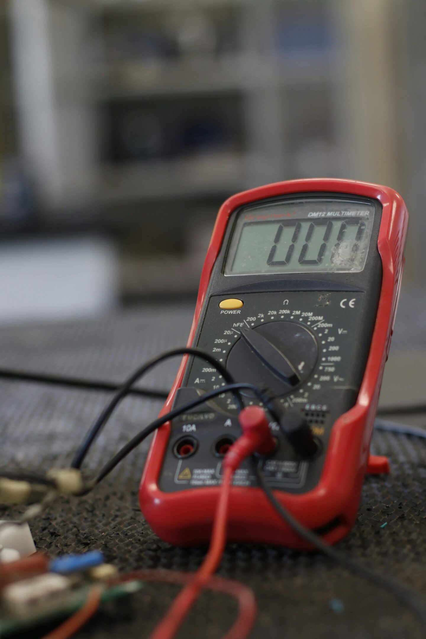 A red digital multimeter sitting on top of a table.